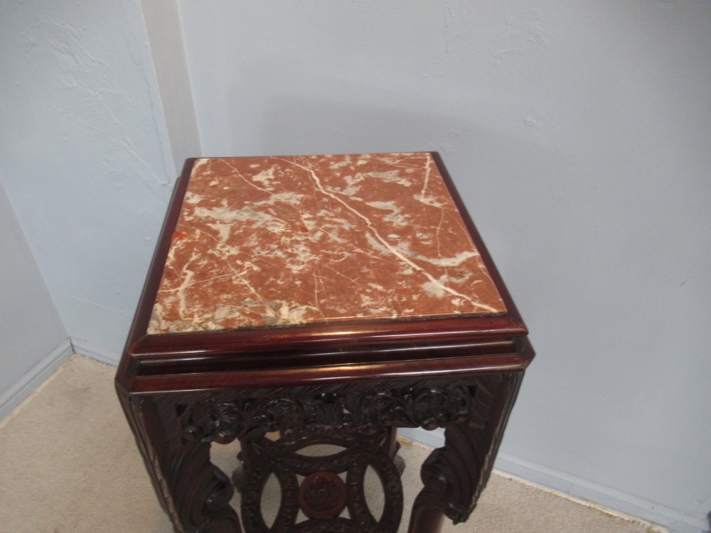 A tall carved dark hardwood stand featuring an inset rectangular pink marble top, ornate pierced apron, and a carved lower shelf. View III