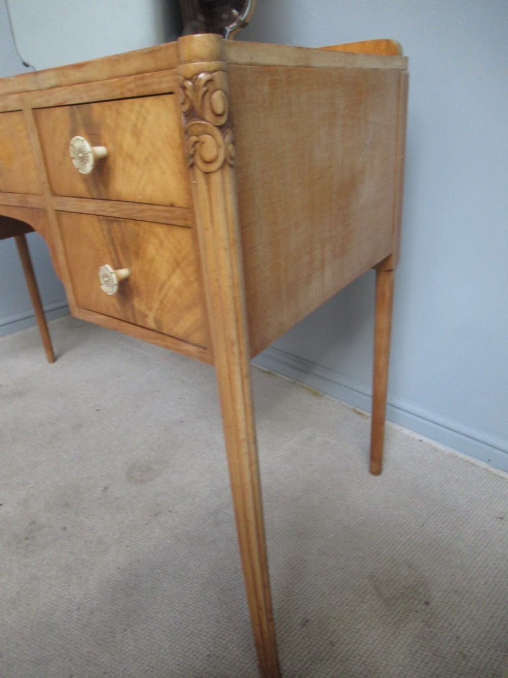 A 1930s Art Deco dressing table made from pale mahogany and maple, featuring an attached arched mirror, five drawers, and slender carved legs. View V