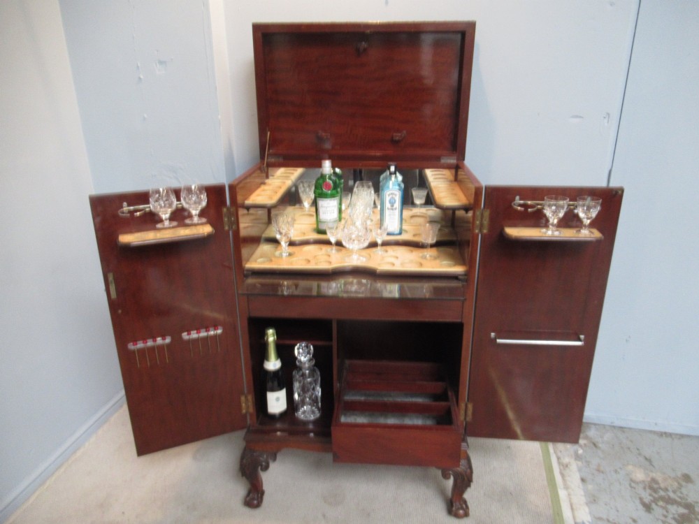 A mahogany Chippendale style cocktail cabinet shown open, revealing a mirrored interior, glass rack holders, and carved cabriole legs with ball-and-claw feet. View II