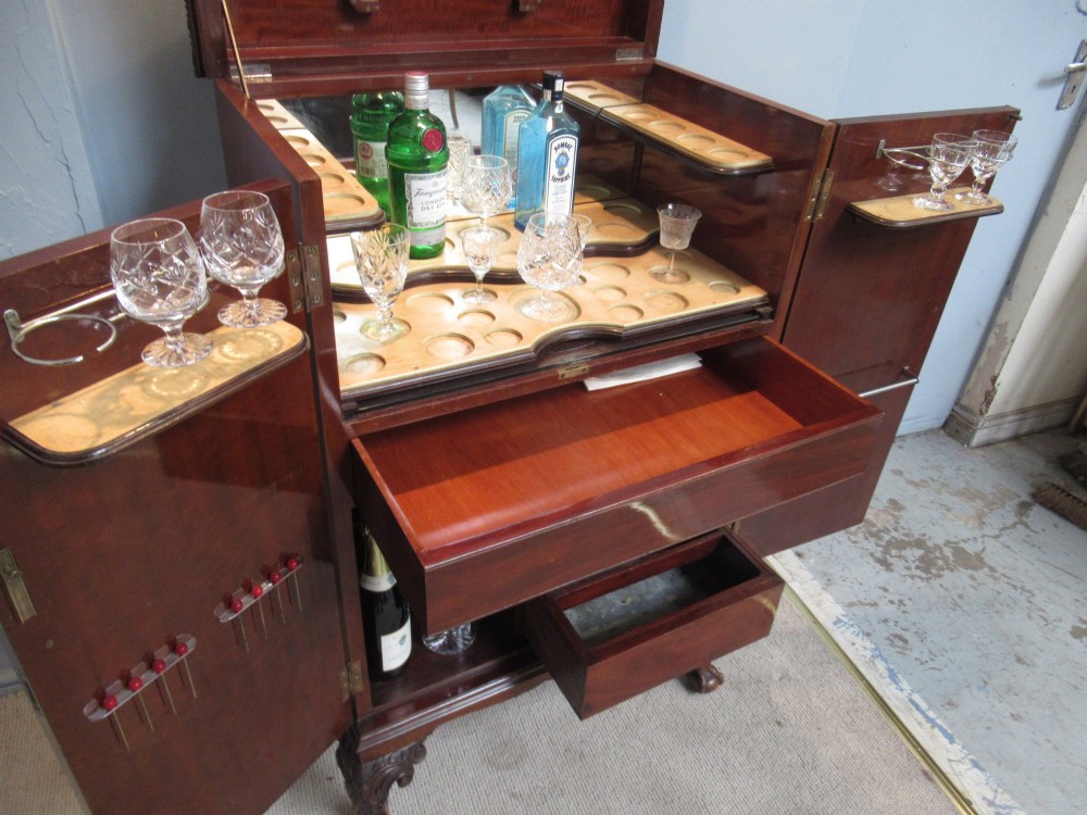 A mahogany Chippendale style cocktail cabinet shown open, revealing a mirrored interior, glass rack holders, and carved cabriole legs with ball-and-claw feet. View IV