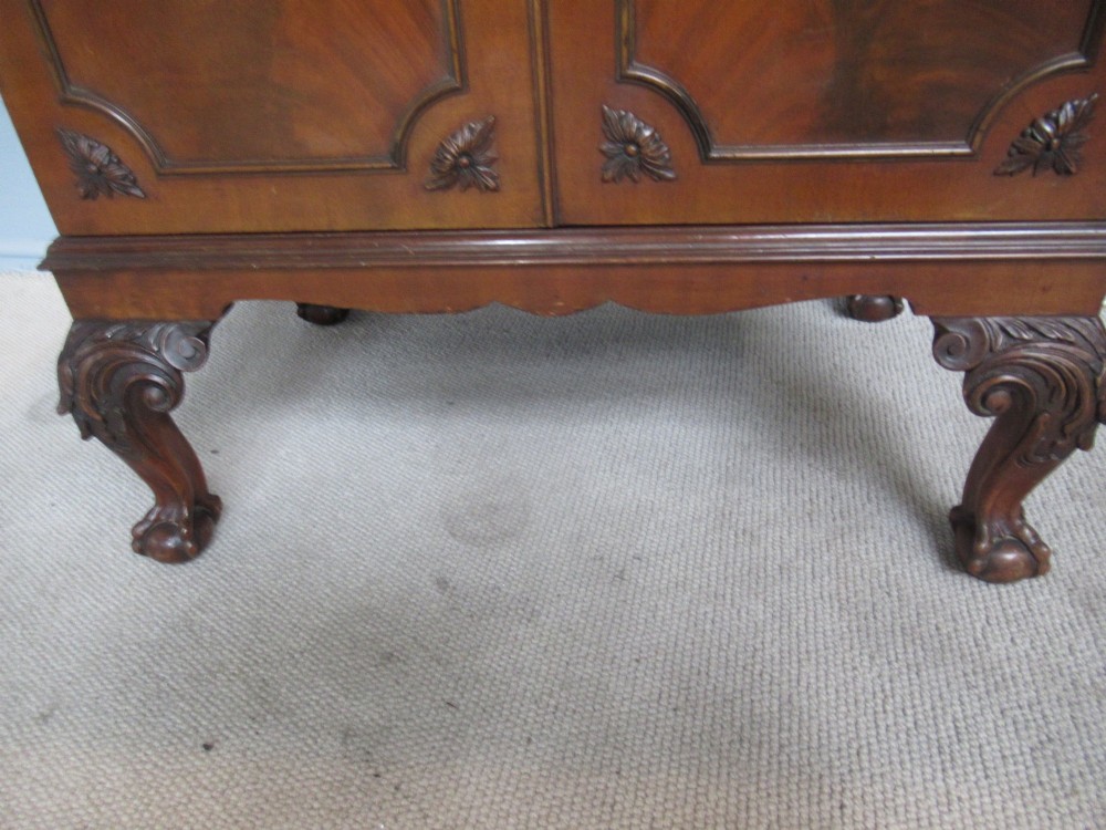 A mahogany Chippendale style cocktail cabinet shown open, revealing a mirrored interior, glass rack holders, and carved cabriole legs with ball-and-claw feet. View X