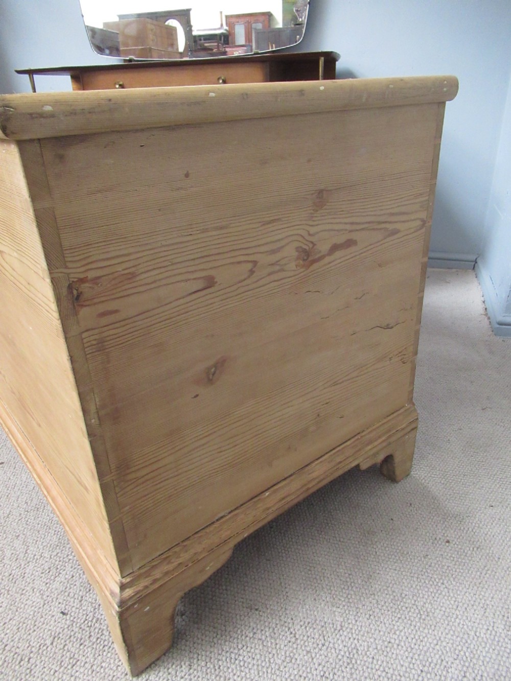 A nineteenth-century pine blanket box featuring a hinged lid, brass escutcheon, and bracket feet. View V