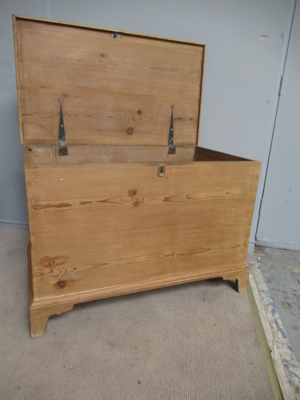 A nineteenth-century pine blanket box featuring a hinged lid, brass escutcheon, and bracket feet. View IX