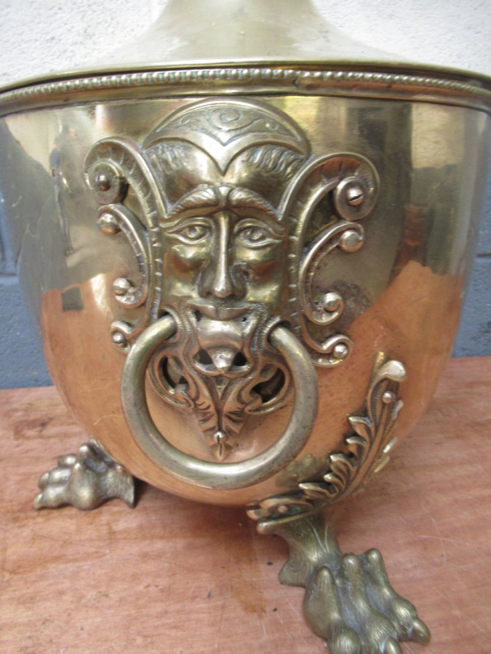 A polished brass lidded decorative bucket with a finial handle, lion mask side rings, and ornate claw feet. View IV