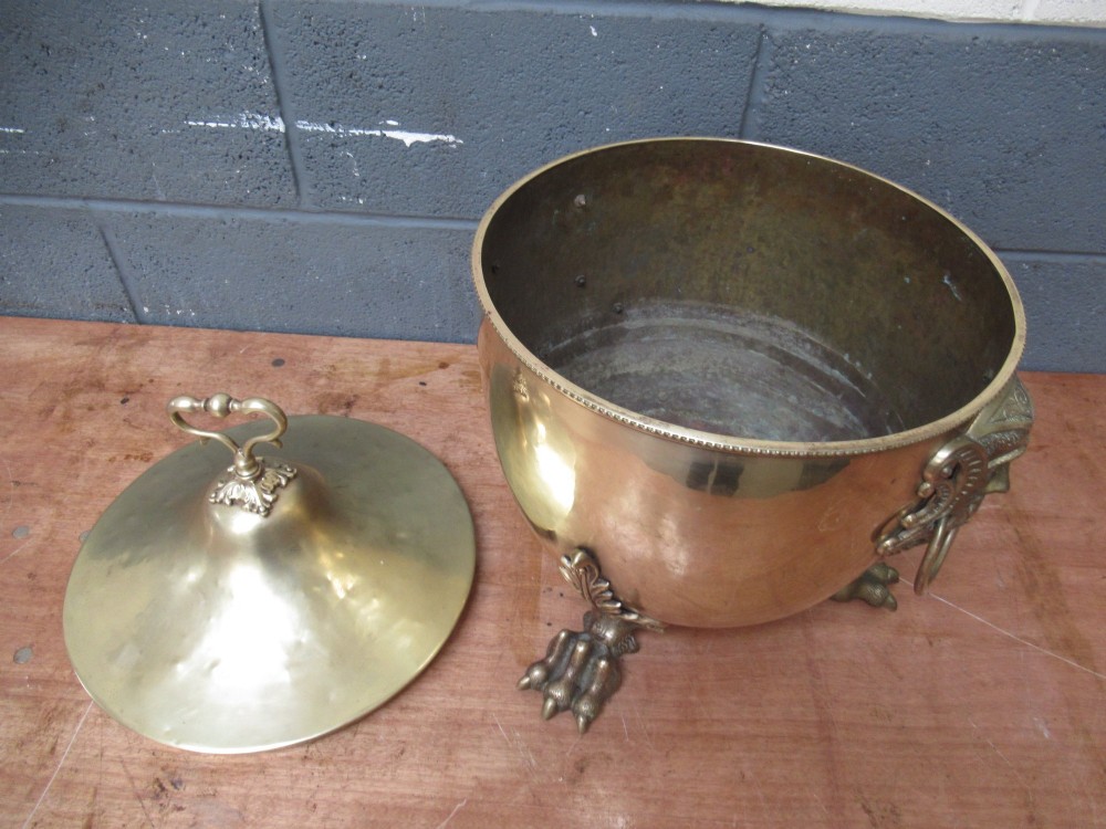 A polished brass lidded decorative bucket with a finial handle, lion mask side rings, and ornate claw feet. View VIII