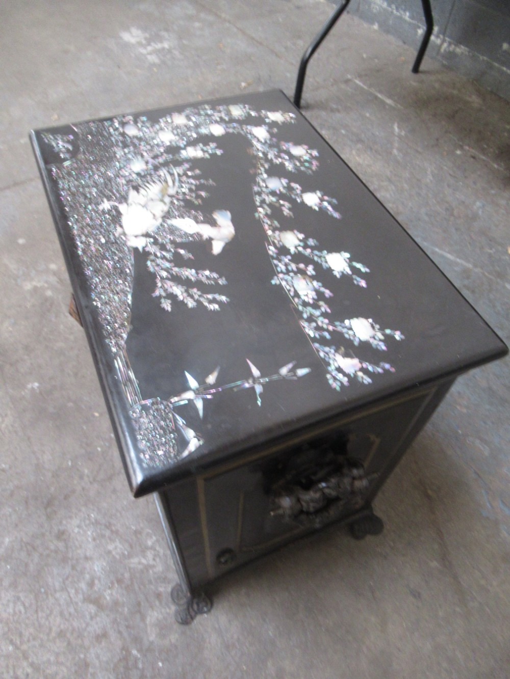 A black metal Victorian coal box featuring mother of pearl inlay depictions of a bird and floral branches, resting on cast metal feet. View II