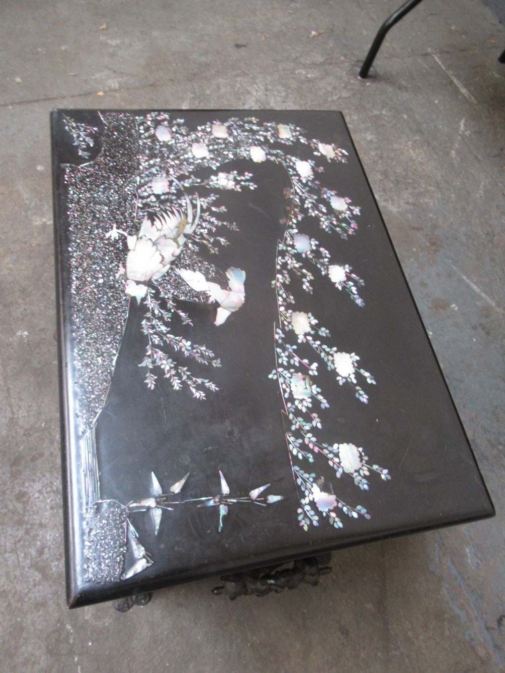 A black metal Victorian coal box featuring mother of pearl inlay depictions of a bird and floral branches, resting on cast metal feet. View III