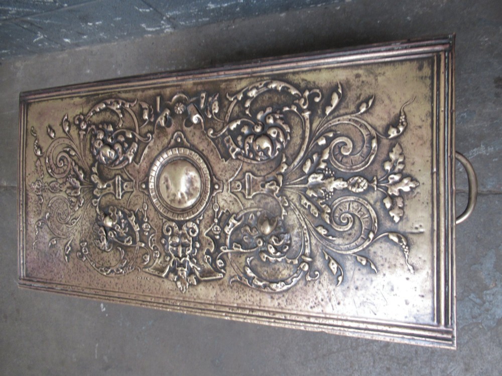 A rectangular Victorian brass log box featuring a detailed embossed relief scene of figures inside a room on the front panel. View IX