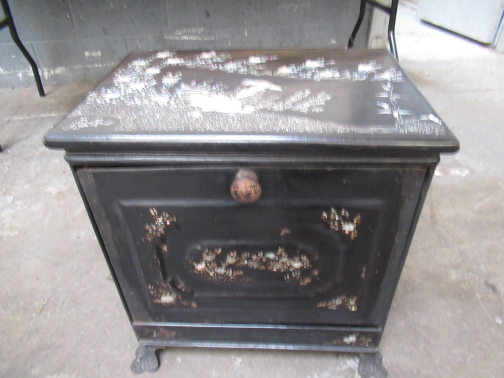 A black metal Victorian coal box featuring mother of pearl inlay depictions of a bird and floral branches, resting on cast metal feet. View VI