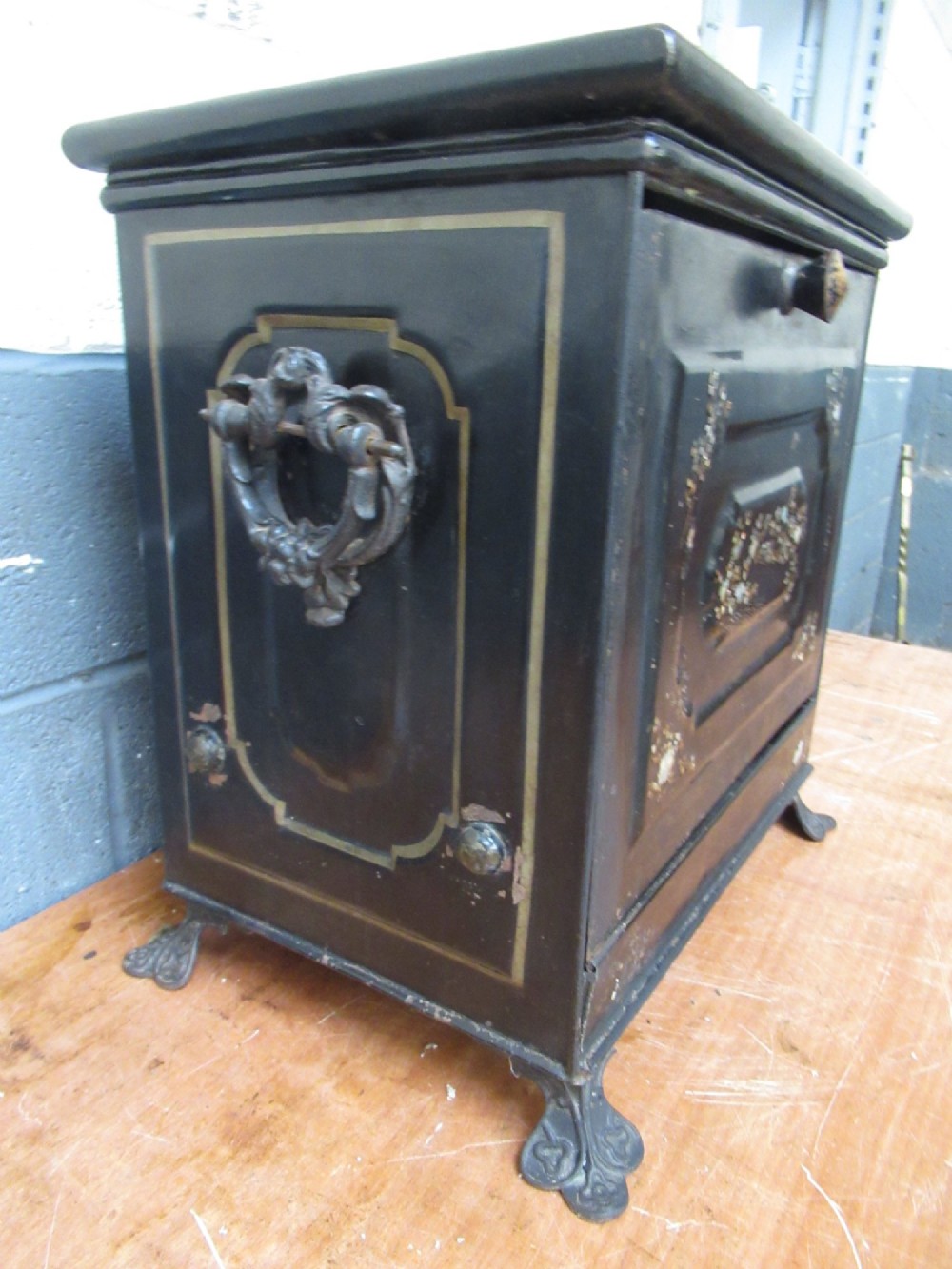 A black metal Victorian coal box featuring mother of pearl inlay depictions of a bird and floral branches, resting on cast metal feet. View IX