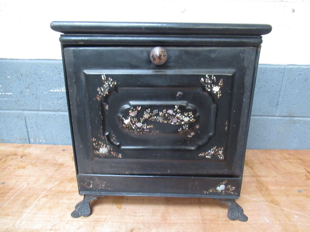 A black metal Victorian coal box featuring mother of pearl inlay depictions of a bird and floral branches, resting on cast metal feet. View X