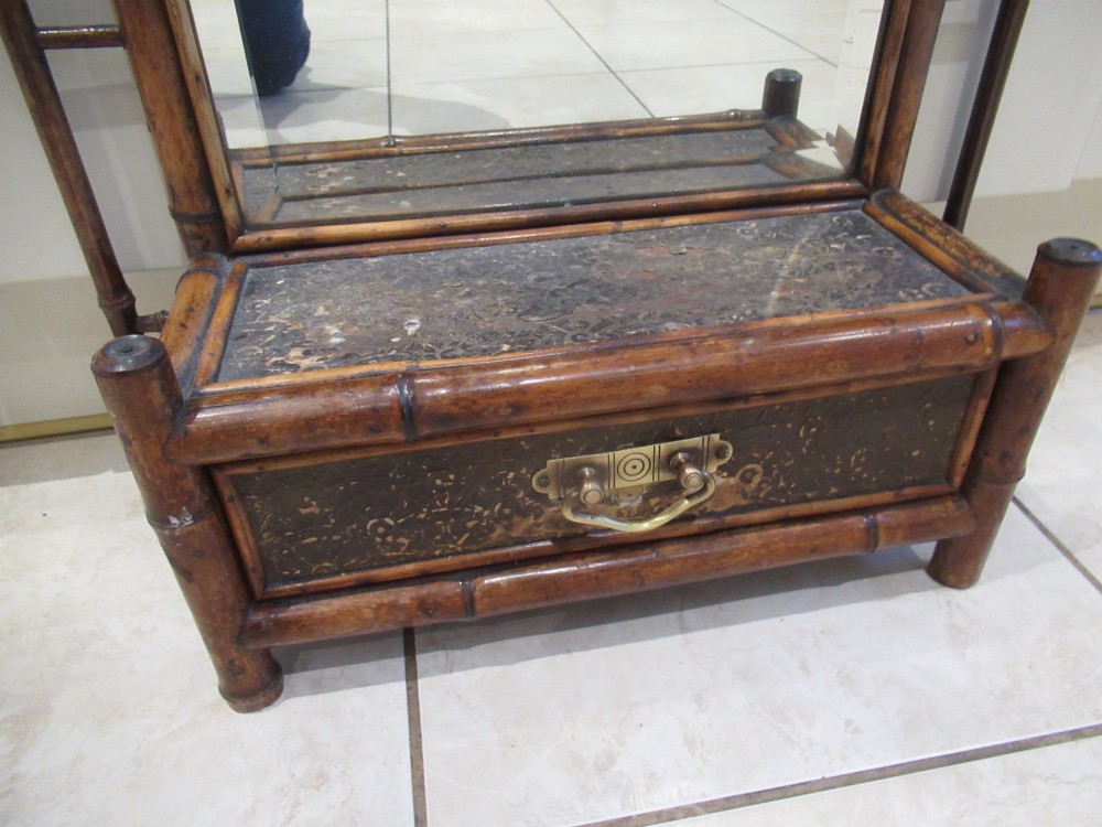 A late Victorian bamboo wall mirror featuring a rectangular bevelled glass plate, bent bamboo scrollwork cresting, side hooks, and a small base drawer with a brass handle. View IV