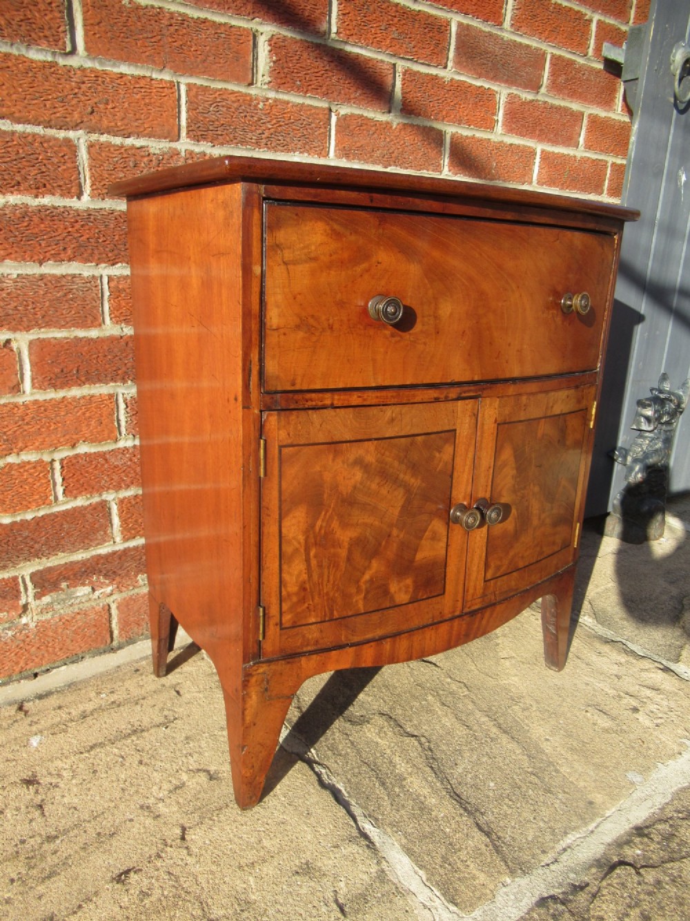 A bowfront Victorian mahogany side cabinet featuring a top drawer and two cupboard doors with flame veneer panels. View II