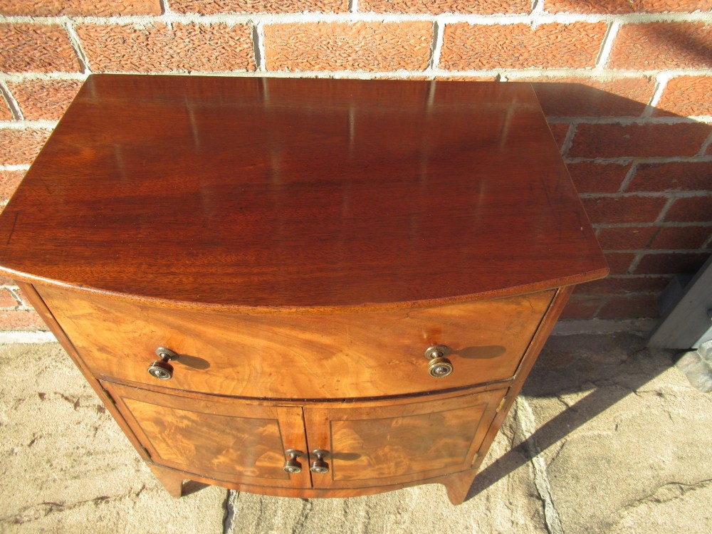 A bowfront Victorian mahogany side cabinet featuring a top drawer and two cupboard doors with flame veneer panels. View IV