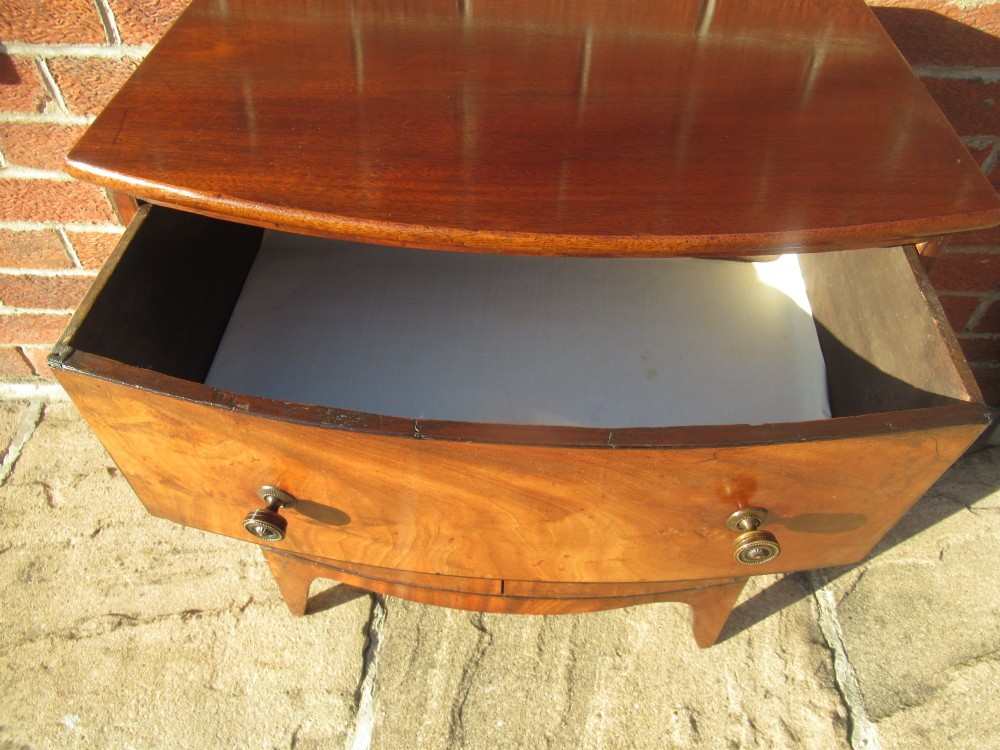 A bowfront Victorian mahogany side cabinet featuring a top drawer and two cupboard doors with flame veneer panels. View V