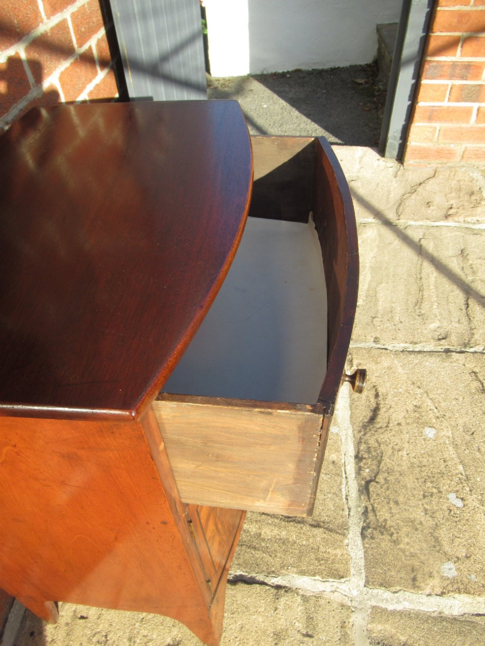 A bowfront Victorian mahogany side cabinet featuring a top drawer and two cupboard doors with flame veneer panels. View VI