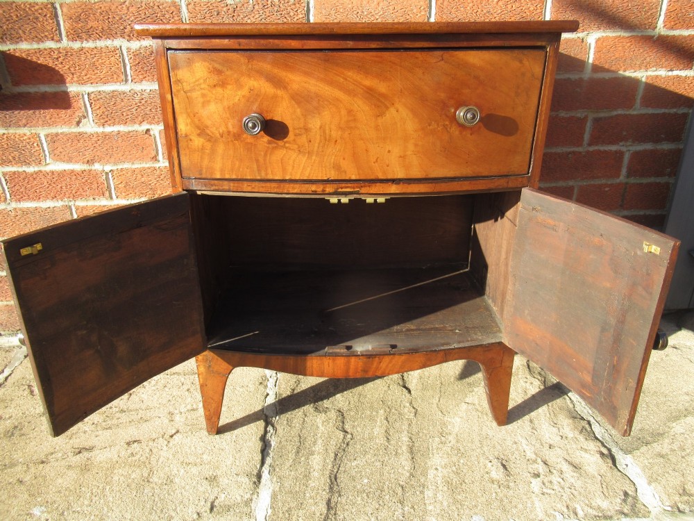 A bowfront Victorian mahogany side cabinet featuring a top drawer and two cupboard doors with flame veneer panels. View VII