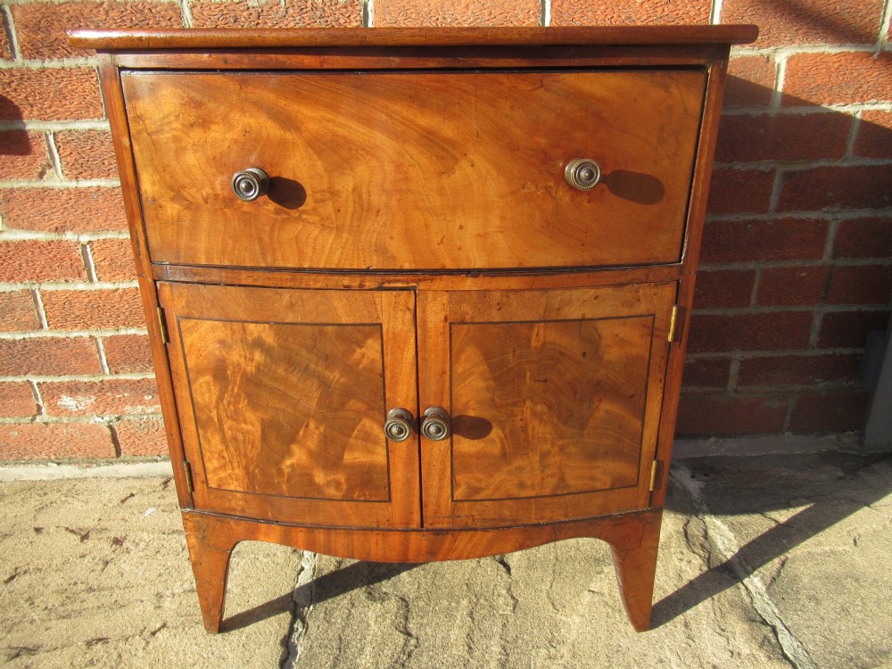 A bowfront Victorian mahogany side cabinet featuring a top drawer and two cupboard doors with flame veneer panels. View IX