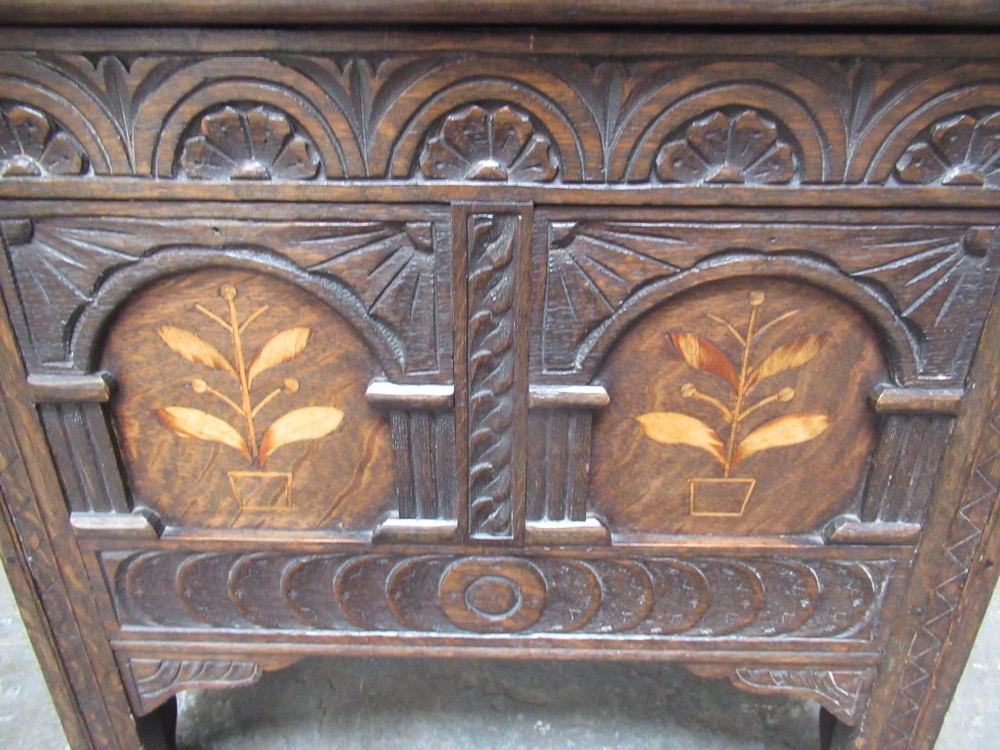 A small dark carved oak coffer featuring two inlaid floral panels, carved arches, and a flat top lid. View III