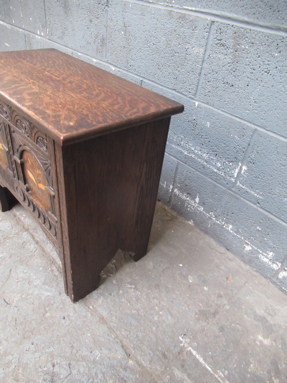 A small dark carved oak coffer featuring two inlaid floral panels, carved arches, and a flat top lid. View V