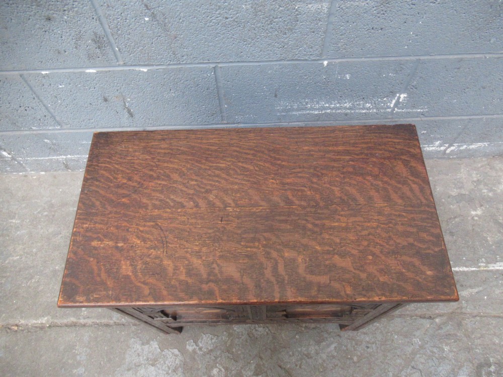 A small dark carved oak coffer featuring two inlaid floral panels, carved arches, and a flat top lid. View VI