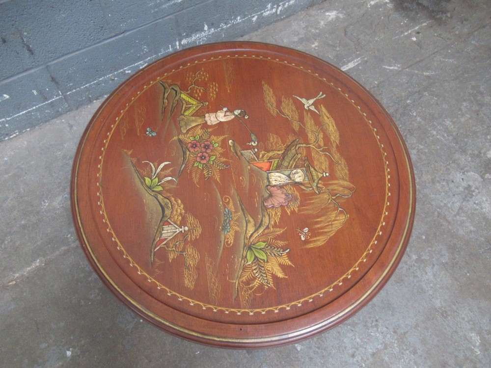 A circular 1930s Chinoiserie coffee table featuring hand-painted oriental figures and flora on a terracotta red lacquered top with gilt-decorated cabriole legs. View II