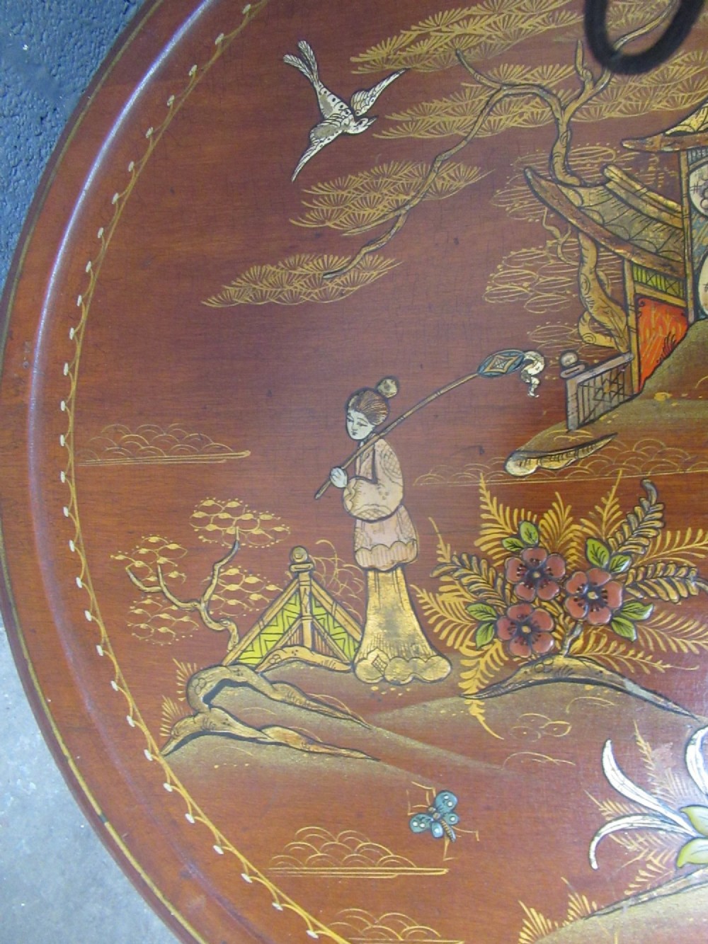 A circular 1930s Chinoiserie coffee table featuring hand-painted oriental figures and flora on a terracotta red lacquered top with gilt-decorated cabriole legs. View III