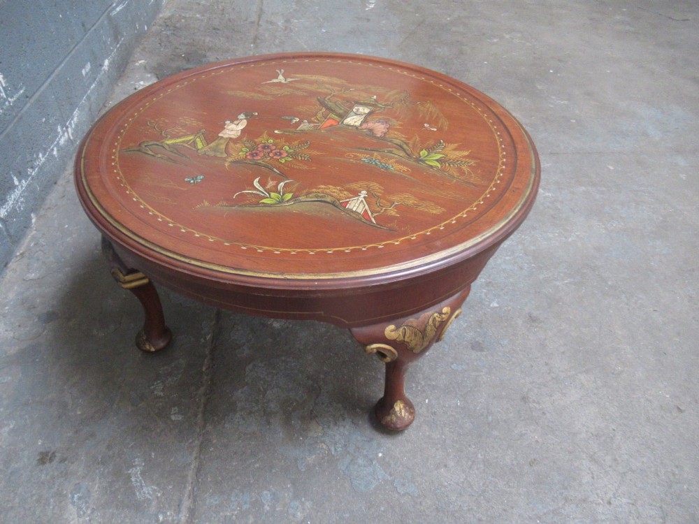 A circular 1930s Chinoiserie coffee table featuring hand-painted oriental figures and flora on a terracotta red lacquered top with gilt-decorated cabriole legs. View V