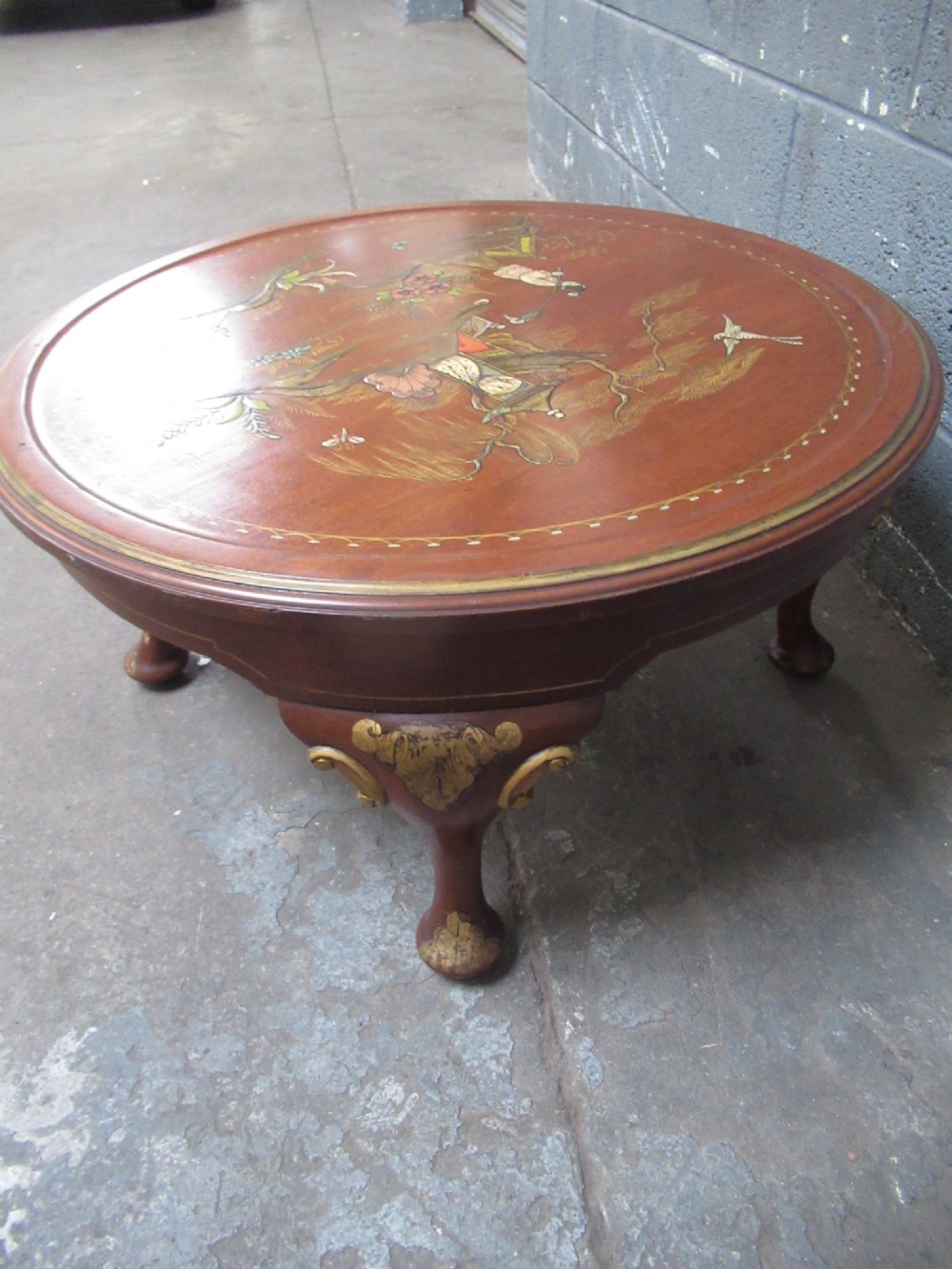 A circular 1930s Chinoiserie coffee table featuring hand-painted oriental figures and flora on a terracotta red lacquered top with gilt-decorated cabriole legs. View VII