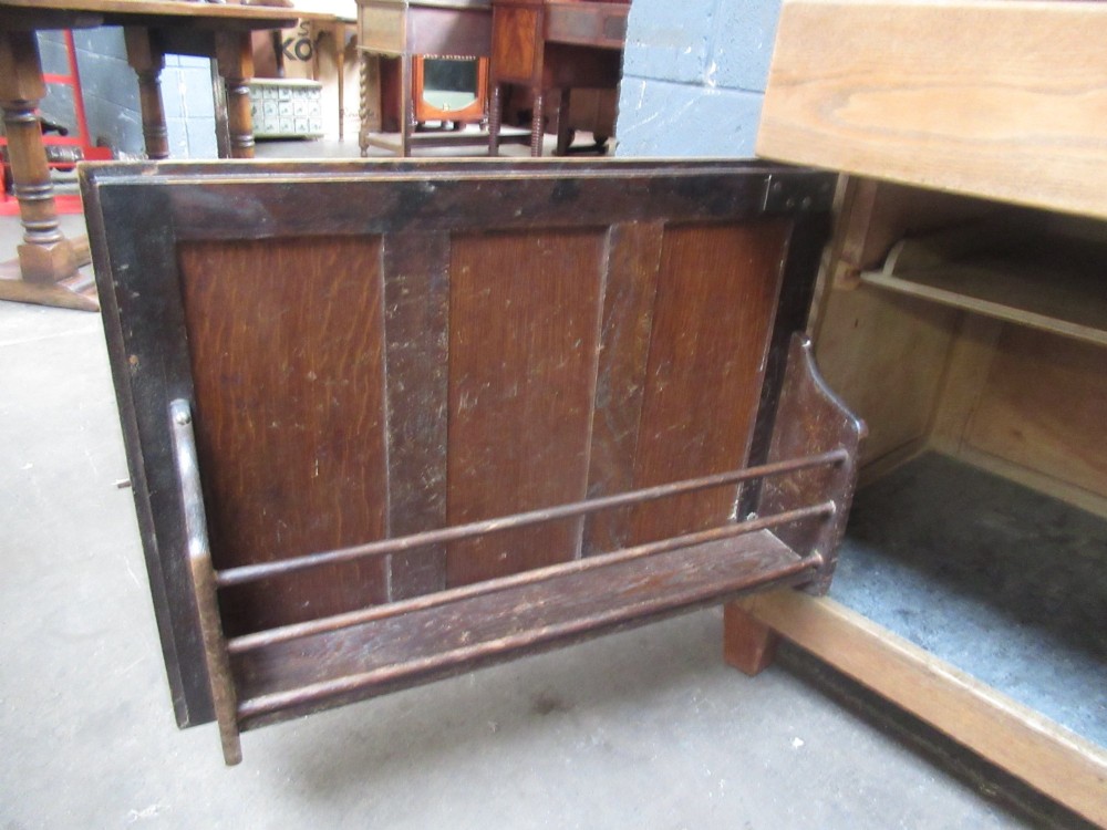 A freestanding 1920s solid oak kitchen cabinet featuring upper and lower panelled cupboards, drawers with glass knobs, and exposed copper hinges. View VII