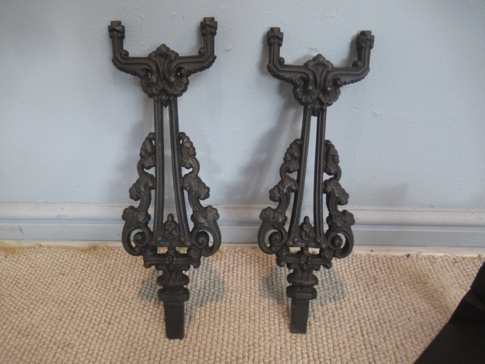A nineteenth-century cast iron fire fender featuring detailed scrolling foliage ornament, a central spear-head rail, and brass feet. View VII