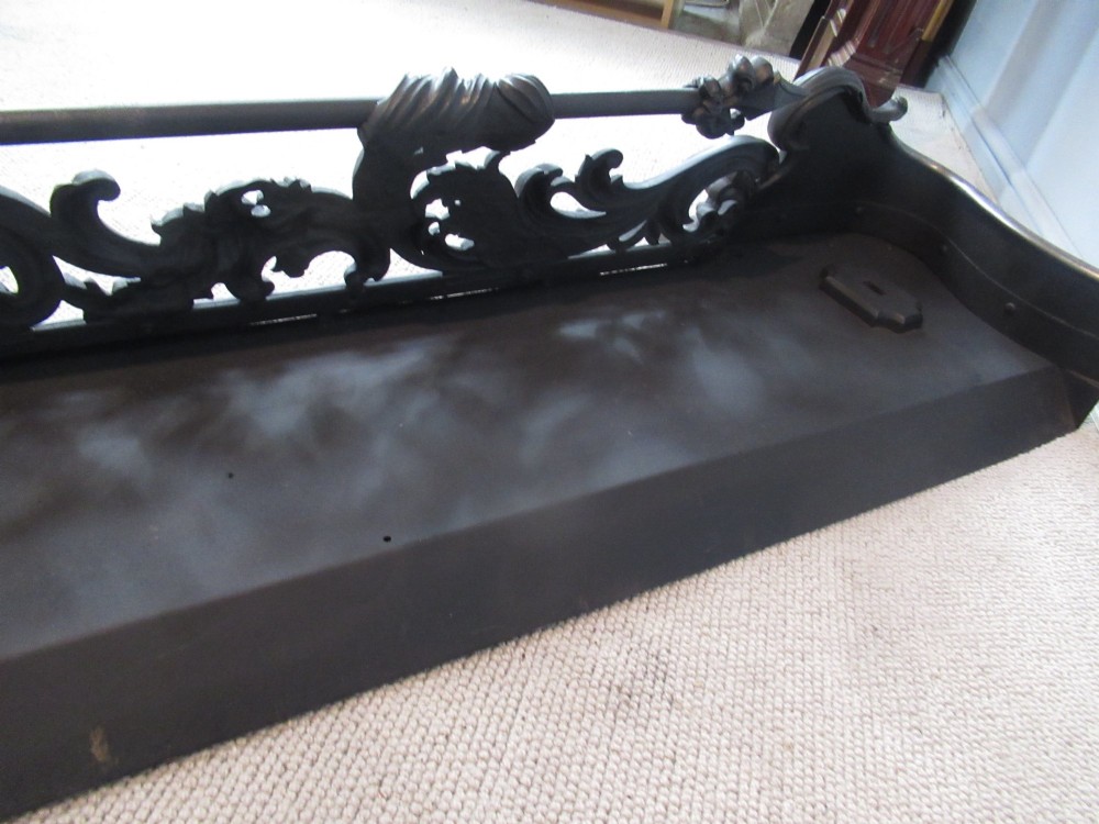 A nineteenth-century cast iron fire fender featuring detailed scrolling foliage ornament, a central spear-head rail, and brass feet. View XIII