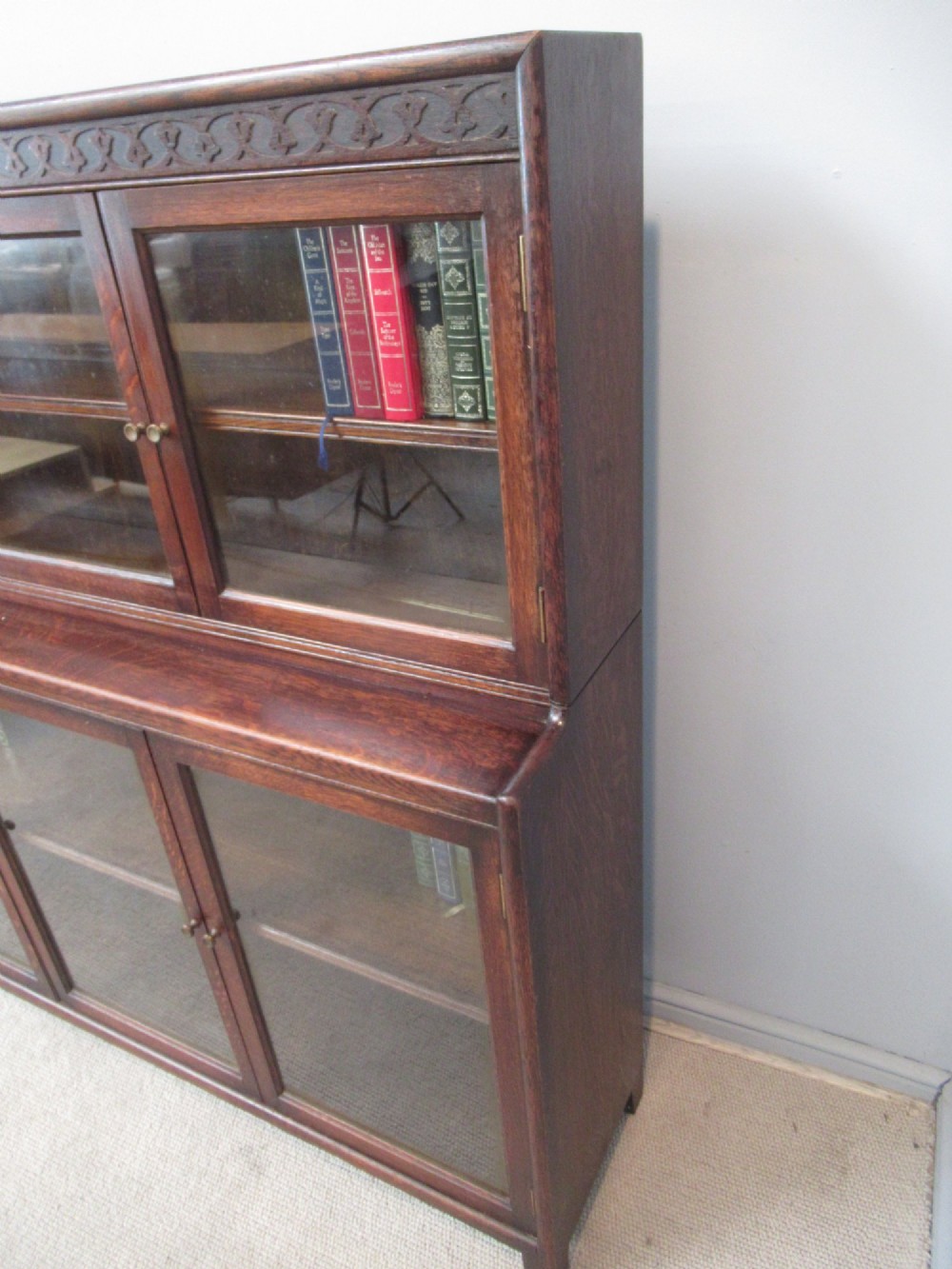 A dark oak two-tiered bookcase featuring six glazed doors, framed glass panels, and a carved top frieze. View II