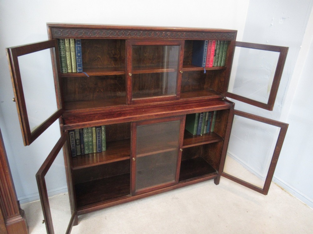 A dark oak two-tiered bookcase featuring six glazed doors, framed glass panels, and a carved top frieze. View IV