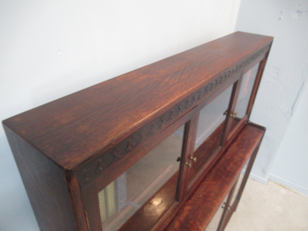 A dark oak two-tiered bookcase featuring six glazed doors, framed glass panels, and a carved top frieze. View IX