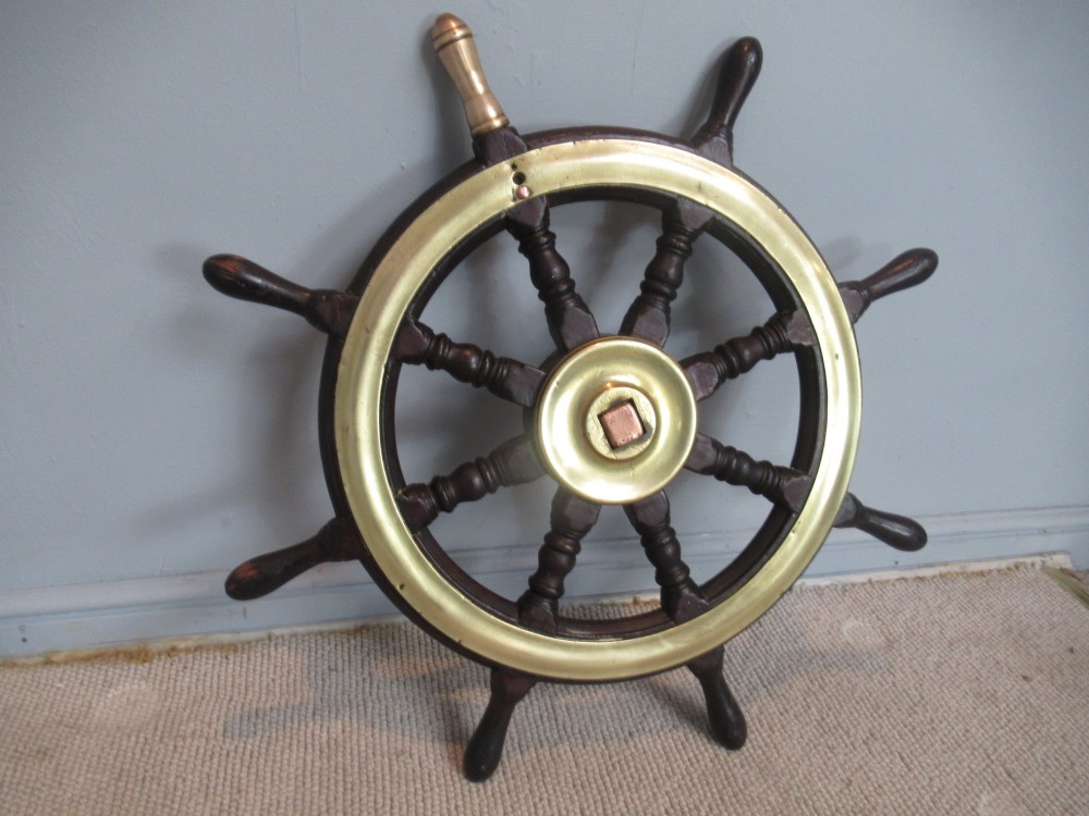A 19th-century turned dark hardwood ships wheel featuring eight handles, a central brass nave plate, and a brass outer brass band. View II