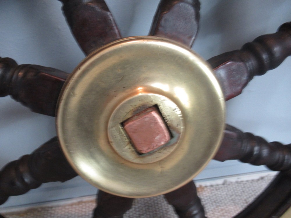 A 19th-century turned dark hardwood ships wheel featuring eight handles, a central brass nave plate, and a brass outer brass band. View III