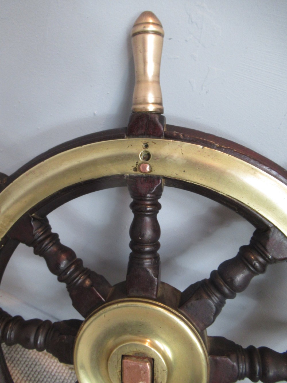 A 19th-century turned dark hardwood ships wheel featuring eight handles, a central brass nave plate, and a brass outer brass band. View IV