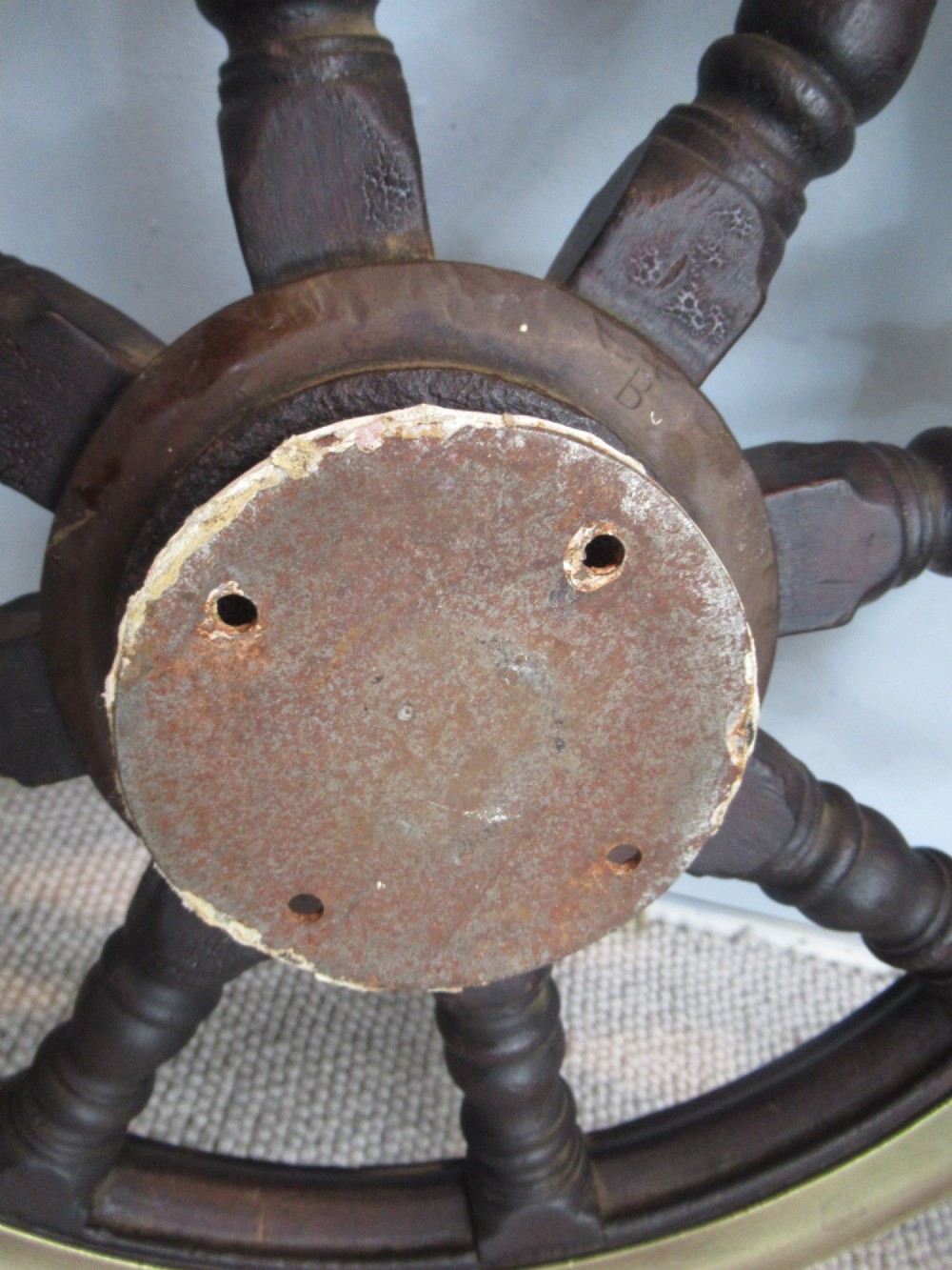 A 19th-century turned dark hardwood ships wheel featuring eight handles, a central brass nave plate, and a brass outer brass band. View V