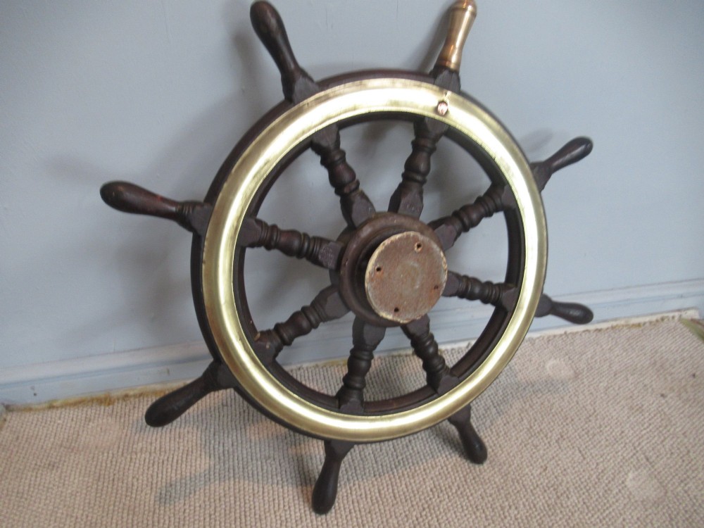 A 19th-century turned dark hardwood ships wheel featuring eight handles, a central brass nave plate, and a brass outer brass band. View VII