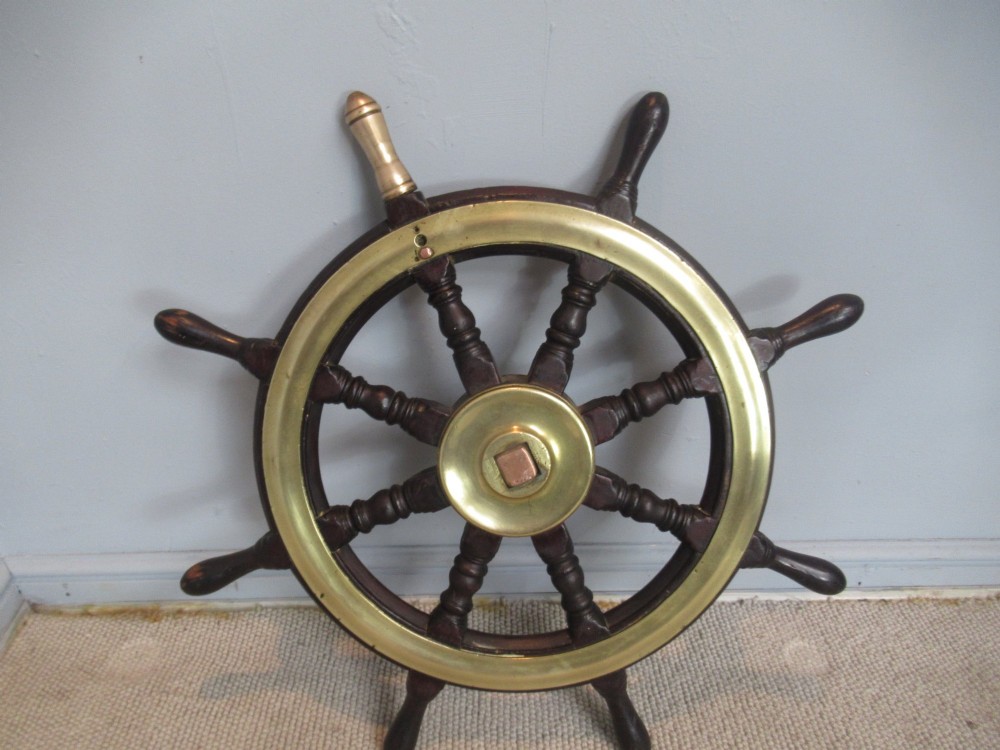A 19th-century turned dark hardwood ships wheel featuring eight handles, a central brass nave plate, and a brass outer brass band. View VIII