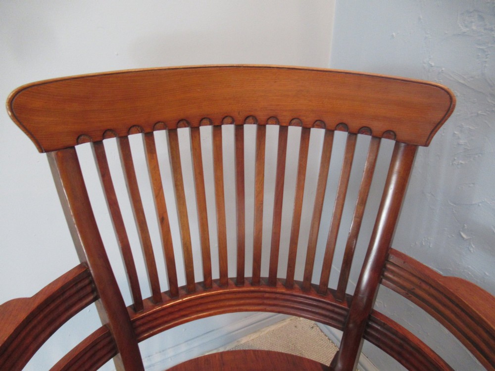 A Victorian walnut swivel office chair with a curved spindle backrest, contoured saddle seat, and quadruped base on castors. View V