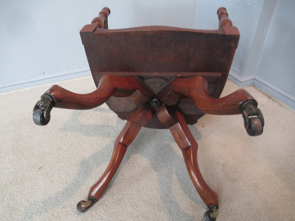 A Victorian walnut swivel office chair with a curved spindle backrest, contoured saddle seat, and quadruped base on castors. View VI