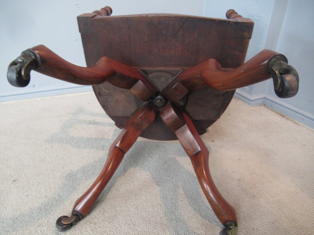 A Victorian walnut swivel office chair with a curved spindle backrest, contoured saddle seat, and quadruped base on castors. View VII