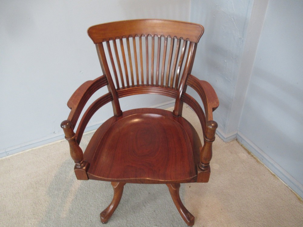 A Victorian walnut swivel office chair with a curved spindle backrest, contoured saddle seat, and quadruped base on castors. View VIII