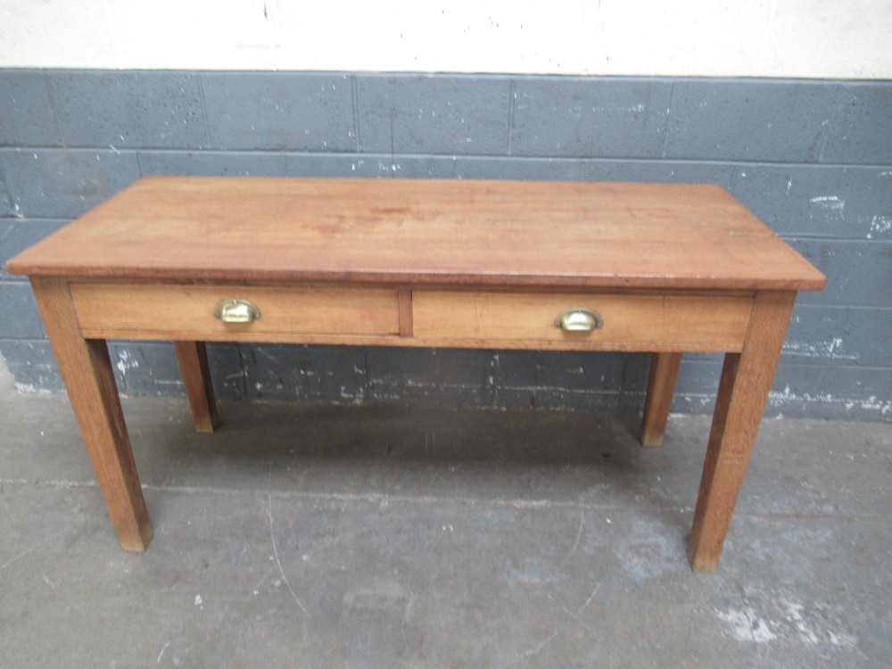 A light oak side table featuring a wide rectangular top, two drawers with brass cup handles, and four straight legs.