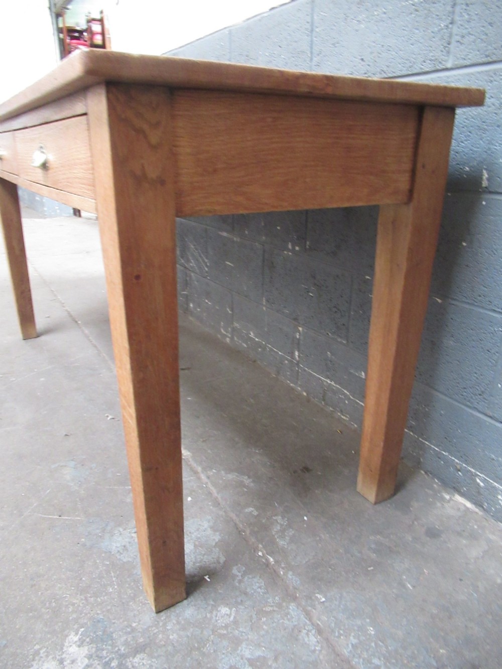 A light oak side table featuring a wide rectangular top, two drawers with brass cup handles, and four straight legs. View IV