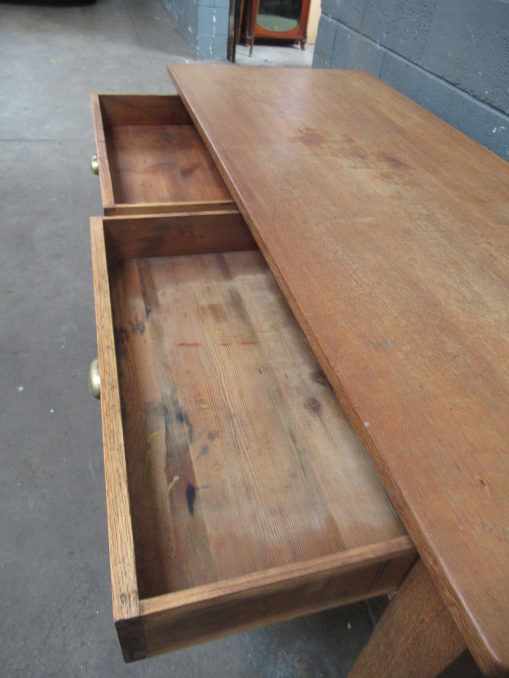 A light oak side table featuring a wide rectangular top, two drawers with brass cup handles, and four straight legs. View VII