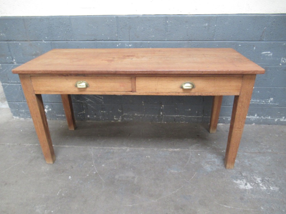 A light oak side table featuring a wide rectangular top, two drawers with brass cup handles, and four straight legs. View X