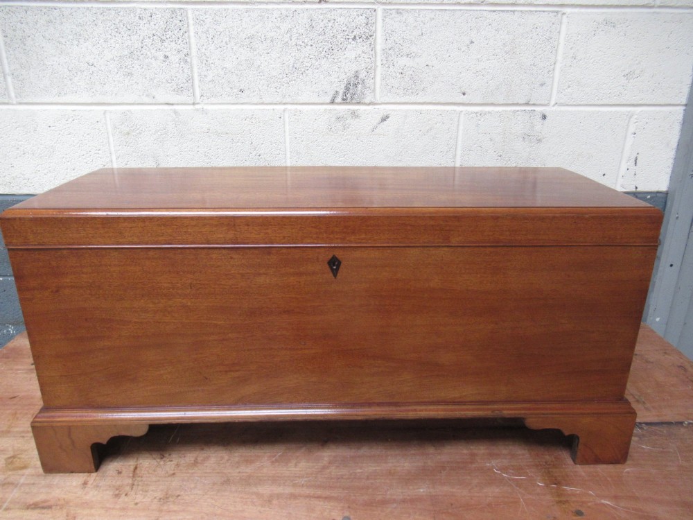 An open mahogany fitted storage chest with internal vertical wood dividers, a keyhole with a dark escutcheon, and a hinged lid. View II
